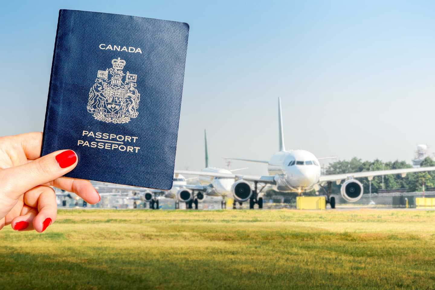 Woman holding Canadian passport on airport background